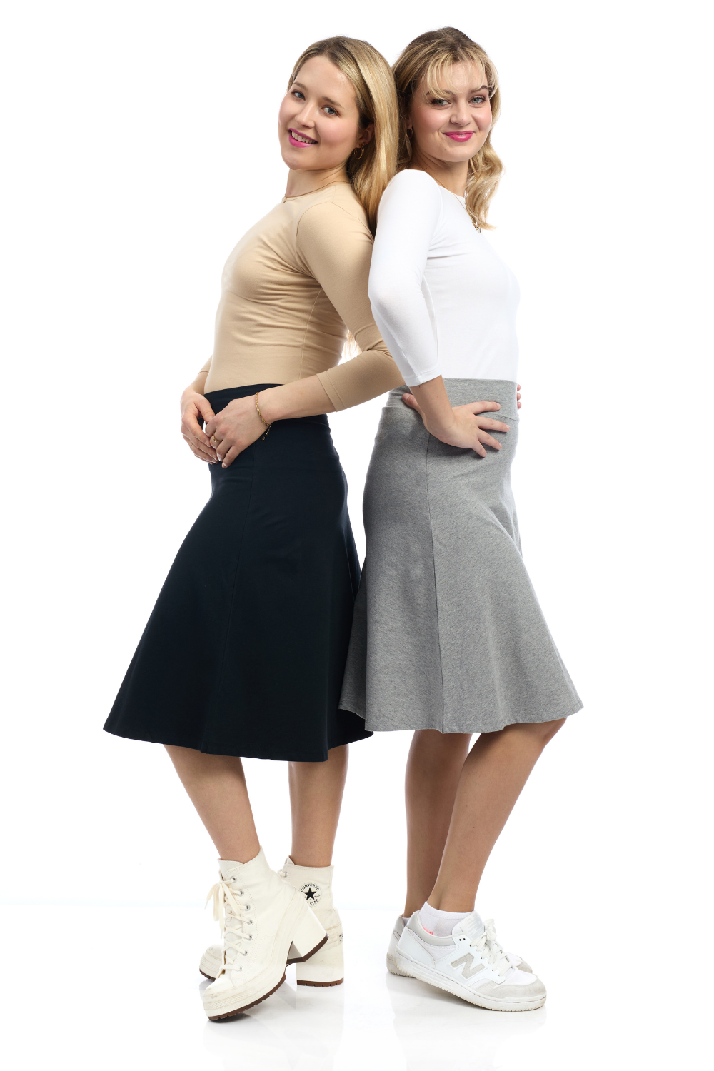 teen age girl wearing a tan color 3/4 sleeve top with a black cotton a-line skirt and a girl in a white top with a heather grey a-line knee length skirt